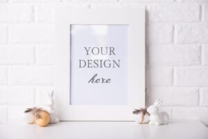 Mock up photo frame near a white brick wall with easter decor.