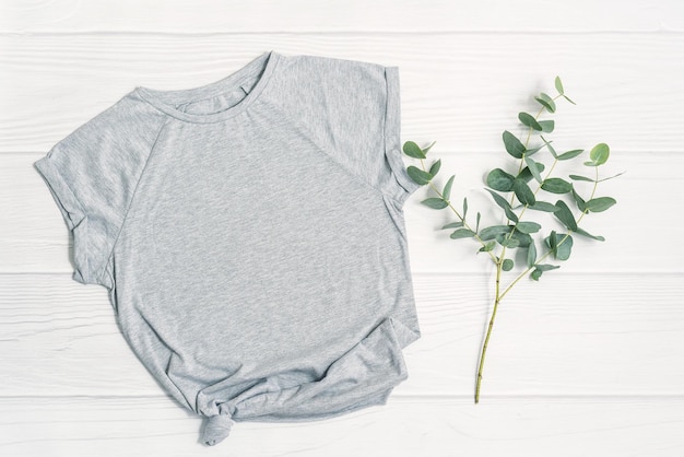 Spring mockup gray tshirt blank template and fresh green eucalyptus plant branch on white wood