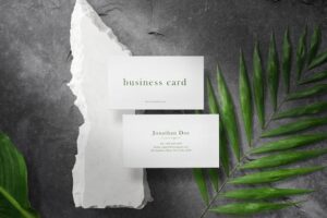 Clean minimal business card mock up on white stone with leaves