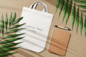 Clean minimal canvas bag mockup on paper background with notebook pen and leaves