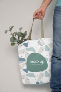 Hand holding tote bag with plants mockup