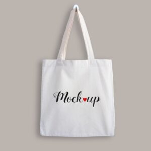Mockup of a white cotton tote bag hanging on a wall