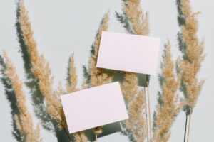 Mockup with blank paper business card and dried pampas grass over pastel blue background