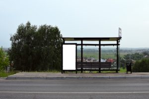 Vertical white billboard at a bus stop on a street background with buildings and road make fun of