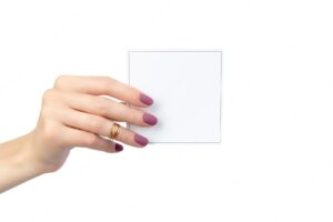 Beautiful womans hand with manicure holding postcard isolated