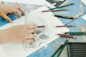Close-up of female sketching skeleton with pencil on workbench