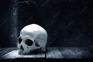 Human skull on wooden table with the dark background