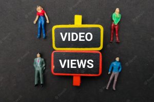 Miniature people and wooden board with the word video views on black background
