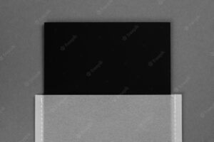 One black colored cardboard mat brand label tag for manufactured items in transparent gray paper case in center on dark gray background tag mock up copy space