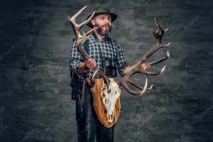 Portrait of hunter man holds a deer's skull.