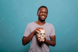 Portrait of male model holding skull from human skeleton to study genetic scientific brain disease, anatomy and biology education. anatomical subject to discover science knowledge.