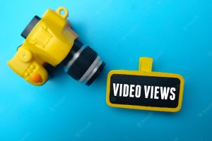 Yellow camera and wooden board with the word video views on blue background