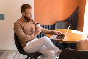 Bearded man working at his desk while holding a cup of coffee