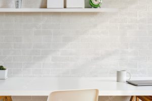 Comfortable workplace with office sullies on wooden table and white brick wall