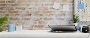 Contemporary working space with laptop camera stationery and supplies on table and brick wall 3d rendering