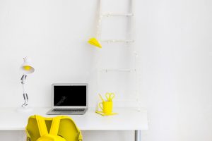 Creative workspace in white and yellow colors with laptop