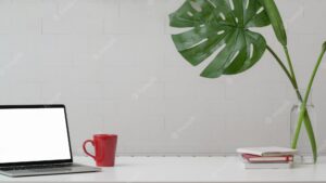 Cropped shot of home office with copy space, laptop, decorations and coffee cup on white table with white wall