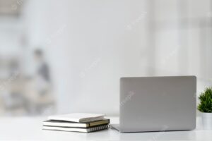 Cropped shot of open laptop computer on wooden table and copy space with blurred office