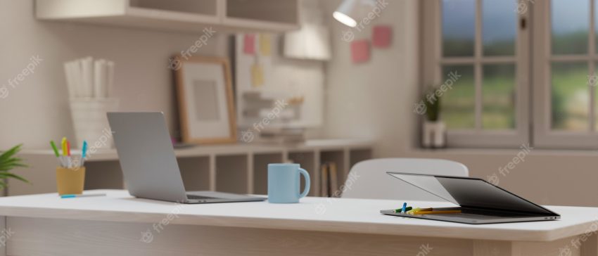 Cropped shot of portable workspace with laptop on wooden table in cozy office room