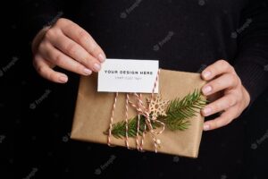 Female hands holding christmas gift box with business card mockup