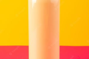 A front view cream colored bottle plastic shampoo can with black cap isolated on the pink-yellow background cosmetics beauty hair