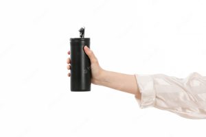 A front view female hand holding black thermos on the white
