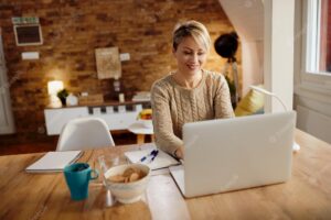 Happy woman using laptop while working at home