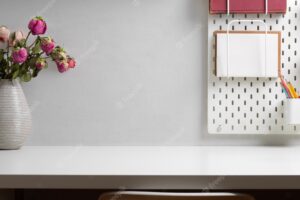 Home office desk with copy space, flower vase and stationery on shelf