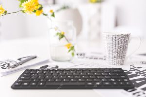 Keyboard with yellow flowers and a cup