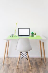 Laptop with blank white screen and markers in holder on desk