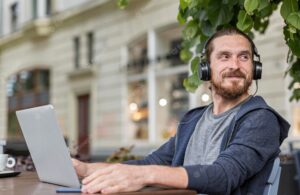 Man with headphones at a city terrace with laptop