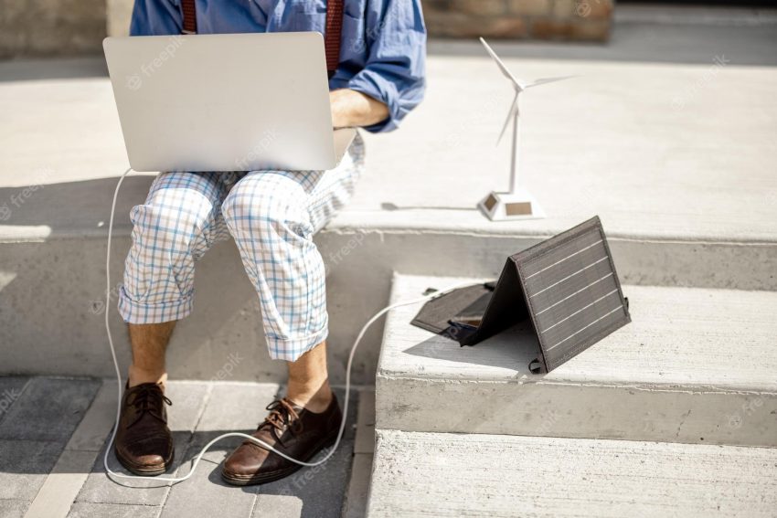 Man works and charges laptop from portable solar panel