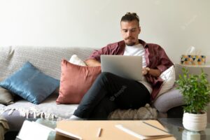 Medium shot man working with laptop on couch