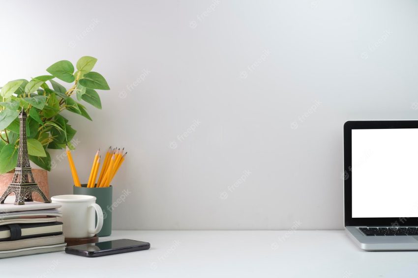 Minimal workplace with laptop computer coffee cup houseplant and stationery on white table copy space for your text
