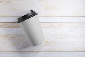 Mock-up of a paper mug that lies on a wooden table. 3d rendering