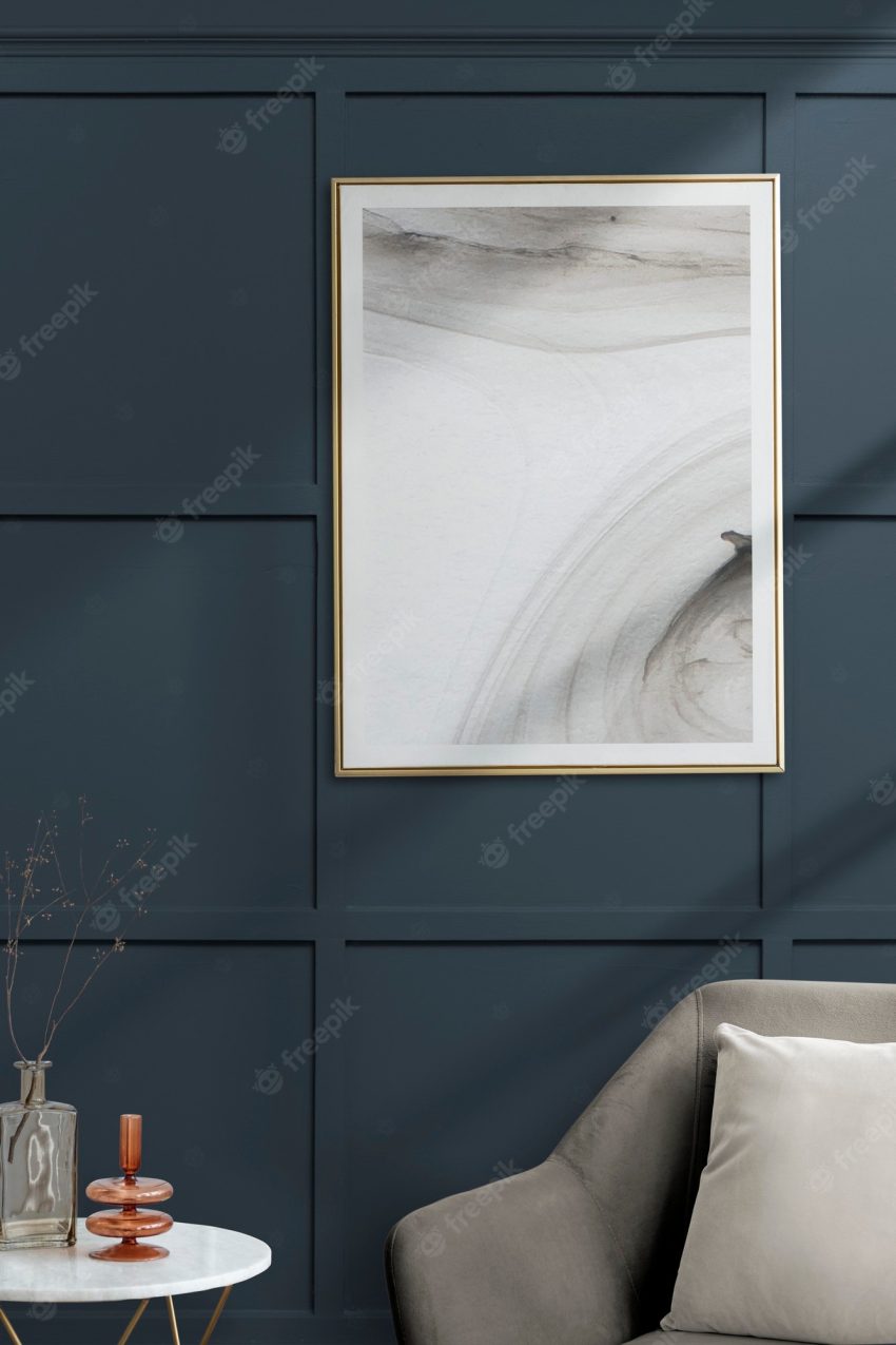 Picture frame with abstract art by a gray velvet armchair