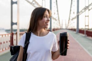 Smiley traveling woman holding thermos on bridge