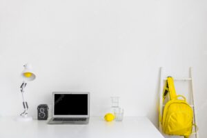 Stylish workplace in white and yellow colors with backpack and laptop