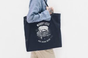 Tattooed woman in a blue linen shirt holding a black tote bag
