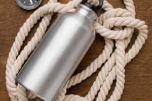 Thermos filled with water and rope with compass