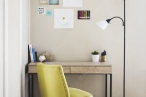 Vertical shot of a yellow chair and tall lamp near a wooden table with books and plant pots on it