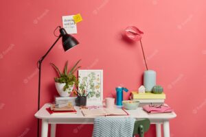 White desk of student with lamp, opened notebook, books, thermos of coffee and rosy calla lilies in vase