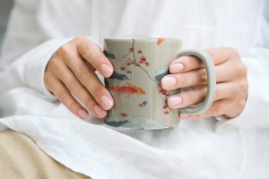 Woman holding a japanese pattern coffee mug, remix of artwork by watanabe seitei