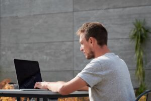 Young man is typing on laptop outdoor
