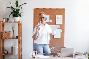 Adult lady in good mood holds coffee cup and poses in office