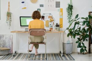 Back view of young businesswoman or freelancer working in front of computer