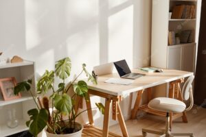 Background image of minimal home interior with laptop on desk and workplace lit by sunlight copy space