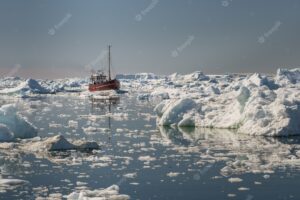 Beautiful view of tourist boat sailing through icebergs in disko bay, greenland
