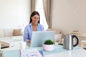 Beautiful woman freelancer noting information for planning project doing remote job via laptop computer girl laughing while reading email on modern laptop device
