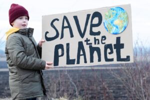 A boy holding a cardboard sign save the planet. farmland preservation concept